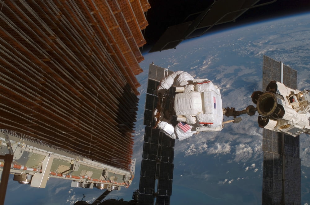 Astronaut works with the port overhead solar array wing on the International Space Station Canvas Art - Stocktrek Images (34 x 23)