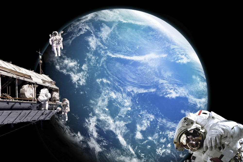 Astronauts perform work on a space station while orbiting above a water covered planet Canvas Art - Marc WardStocktrek Images (18 x 12)
