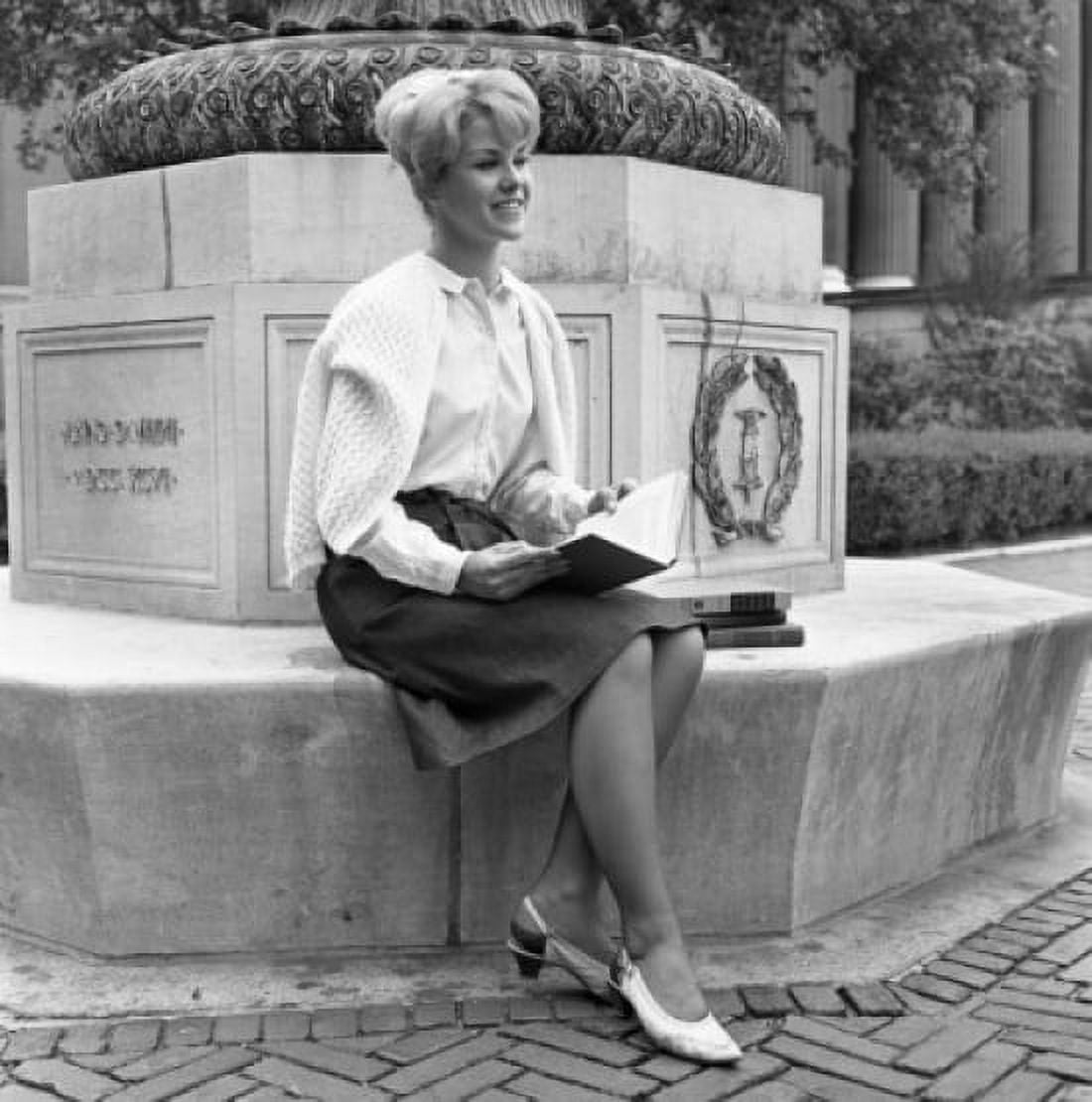 Attractive young woman sitting on monument at university campus Canvas Art - (24 x 36)