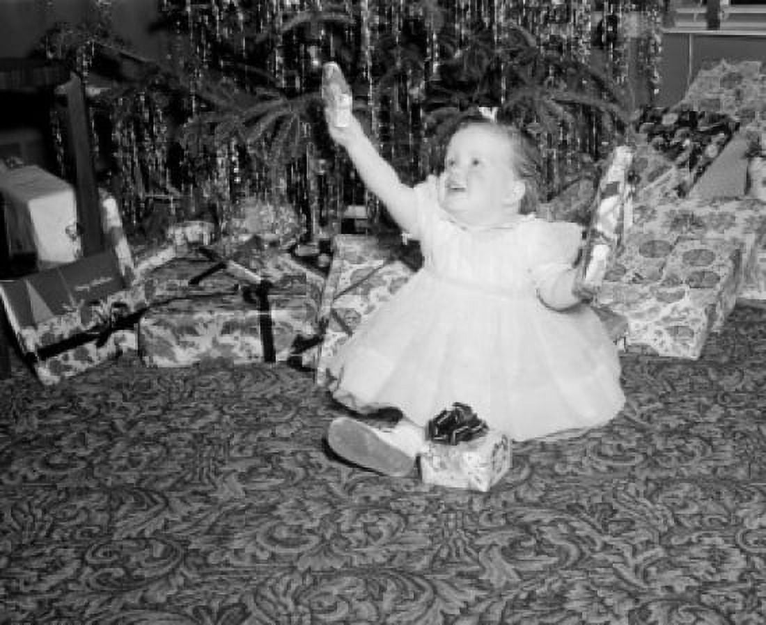 Baby girl holding gifts by Christmas tree Canvas Art - (18 x 24)