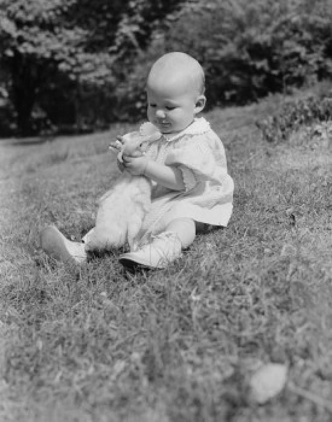Baby girl sitting on grass hugging duck Canvas Art - (18 x 24)