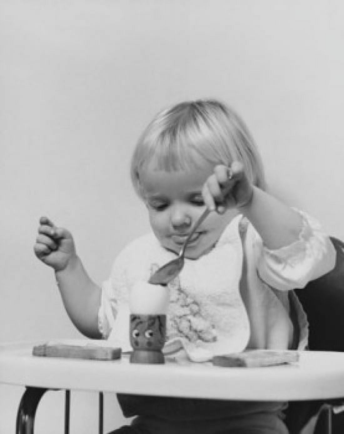 Baby sitting in a high chair and eating an egg Canvas Art - (24 x 36)