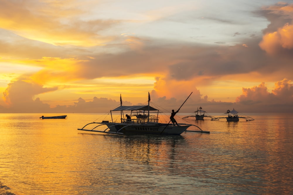 Beautiful sunrise in Alona Beach a man moving his boat to reach the shore with a long stick Panglao Island Bohol Philippines Canvas Art - Luis Martinez Design Pics (38 x 24)