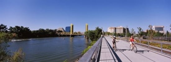 Bicyclists along the Sacramento River with Tower Bridge in background Sacramento Sacramento County California USA Canvas Art - Panoramic Images (36 x 13)