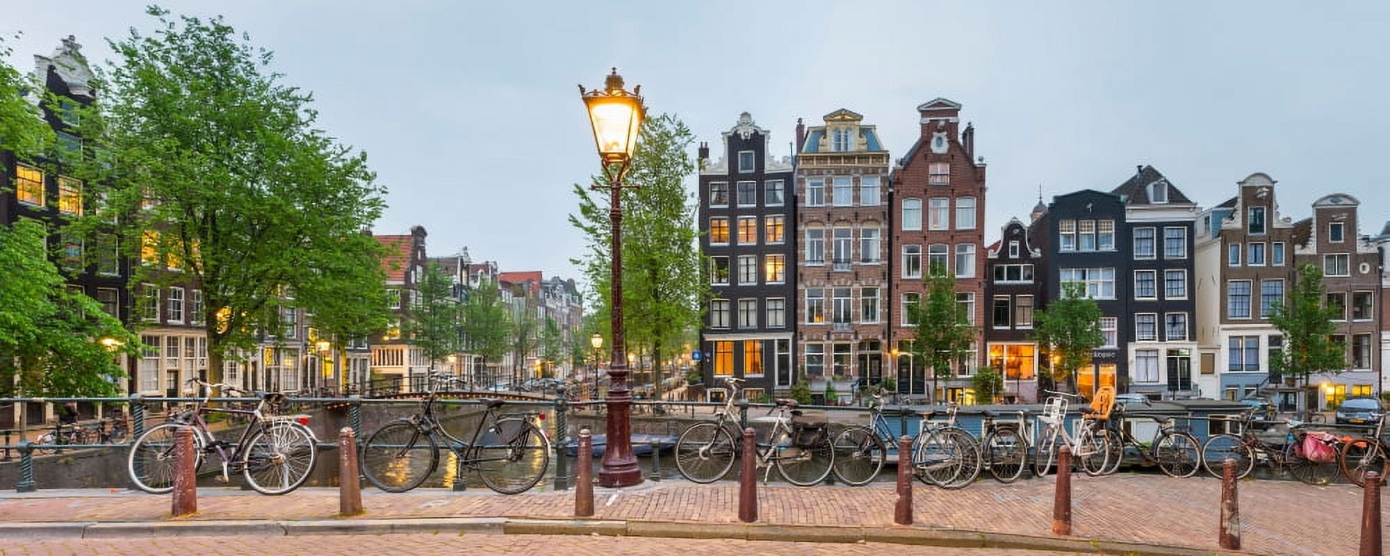 Bikes and houses along canal at dusk at intersection of Herengracht and Brouwersgracht Amsterdam North Holland Netherlands Canvas Art - Panoramic Images (27 x 9)