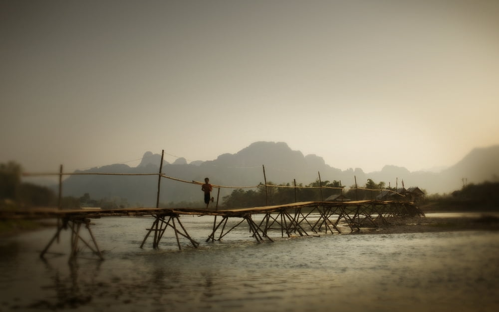 Boy Running Across A Wooden Bridge On A River With Mountains In The Background Vang Vieng Laos Canvas Art - Huy Lam Design Pics (38 x 24)