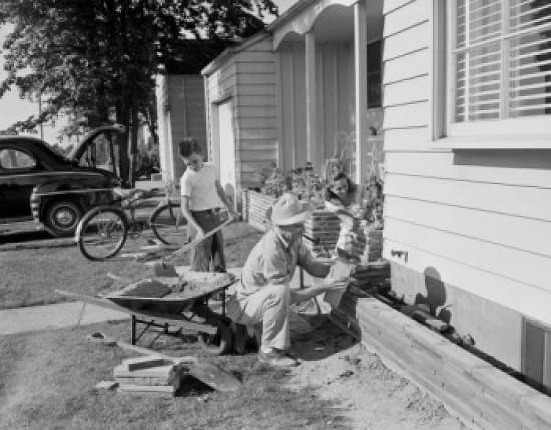 Boy and farther doing small masonry work outside suburban home Canvas Art - (18 x 24)