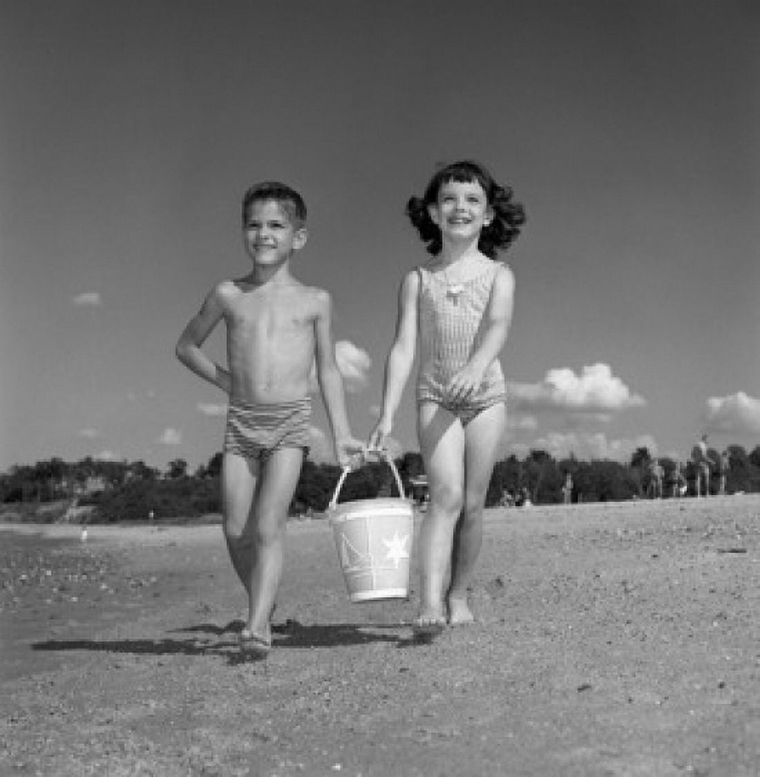 Boy and girl carrying bucket on beach Canvas Art - (24 x 36)