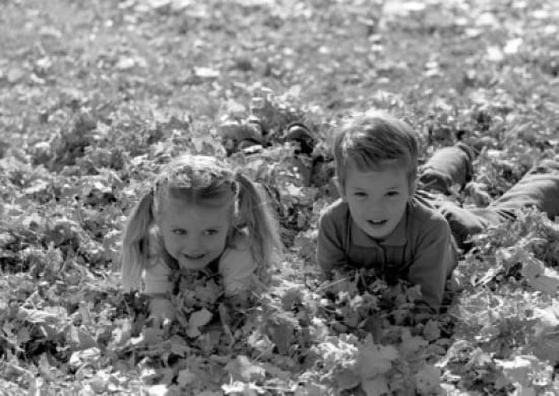 Boy and girl lying down in pile of leaves Canvas Art - (24 x 36)