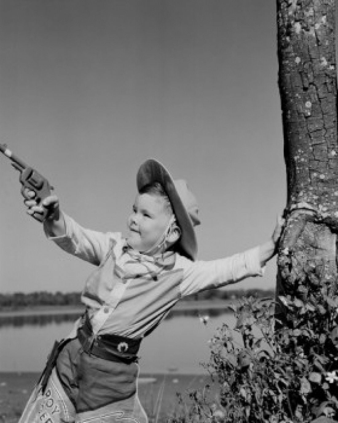 Boy dressed as cowboy playing with toy gun Canvas Art - (24 x 36)