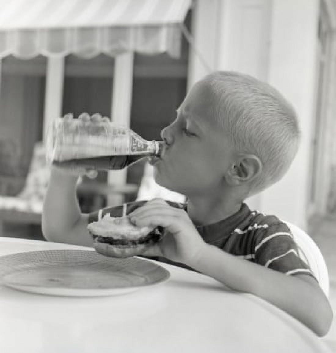 Boy drinking juice from bottle while holding sandwich Canvas Art - (18 x 24)