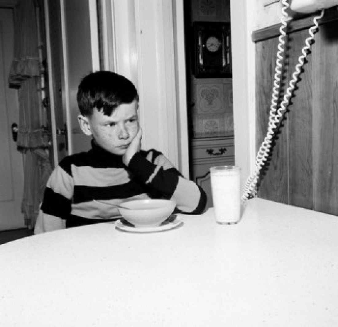 Boy frowning over bowl of cornflakes and glass of milk Canvas Art - (24 x 36)