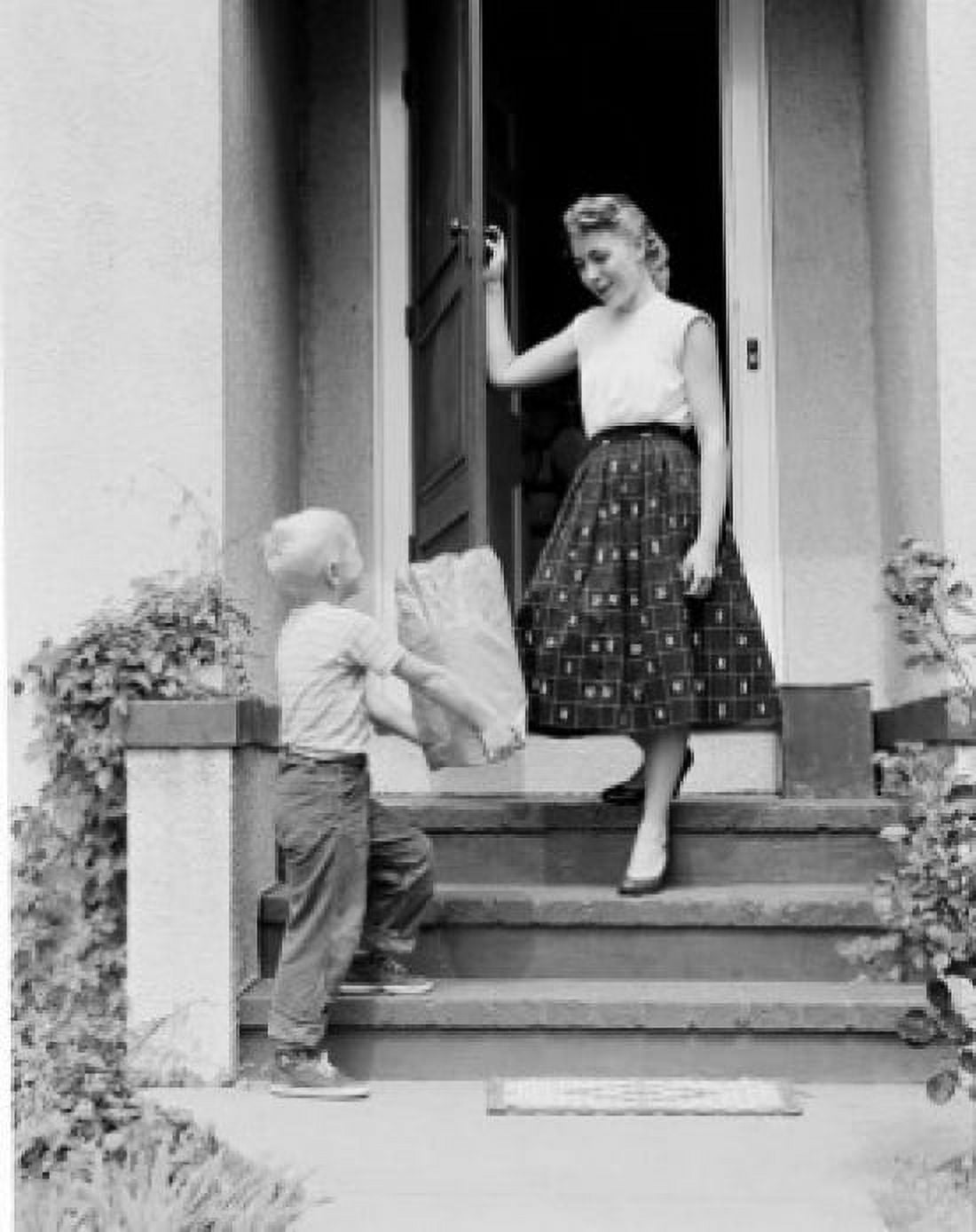 Boy giving shopping bag to mother outside house Canvas Art - (24 x 36)