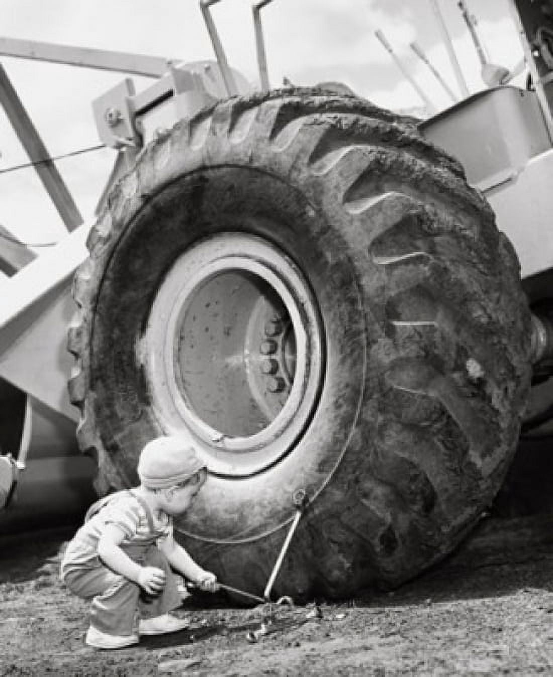 Boy holding a tool and crouching near a bulldozer Canvas Art - (24 x 36)