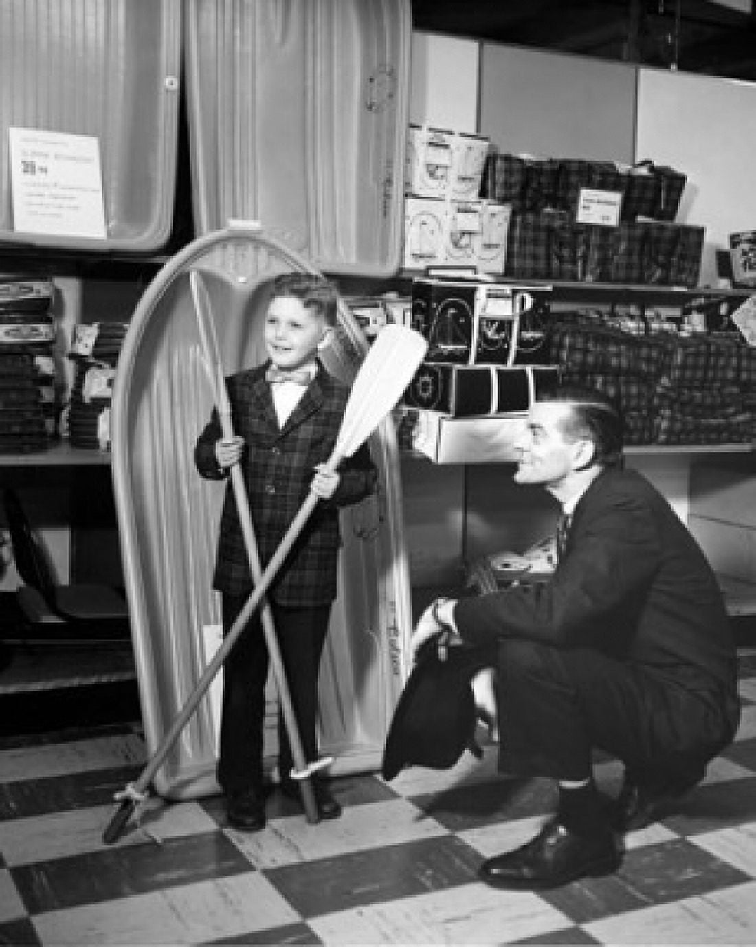Boy holding two oars in a store and a salesman looking at him Canvas Art - (18 x 24)