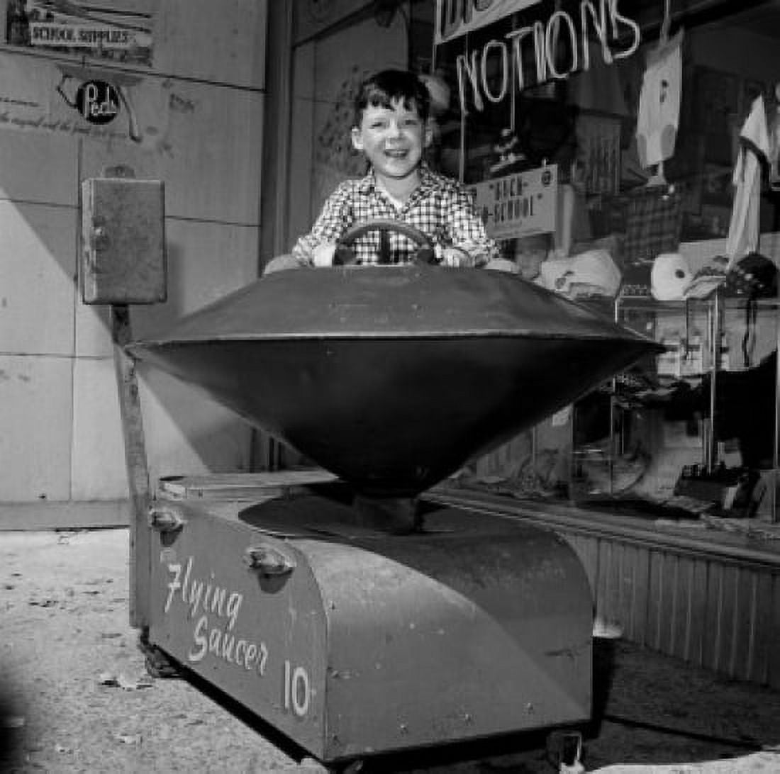 Boy in toy ride outside store Canvas Art - (18 x 24)