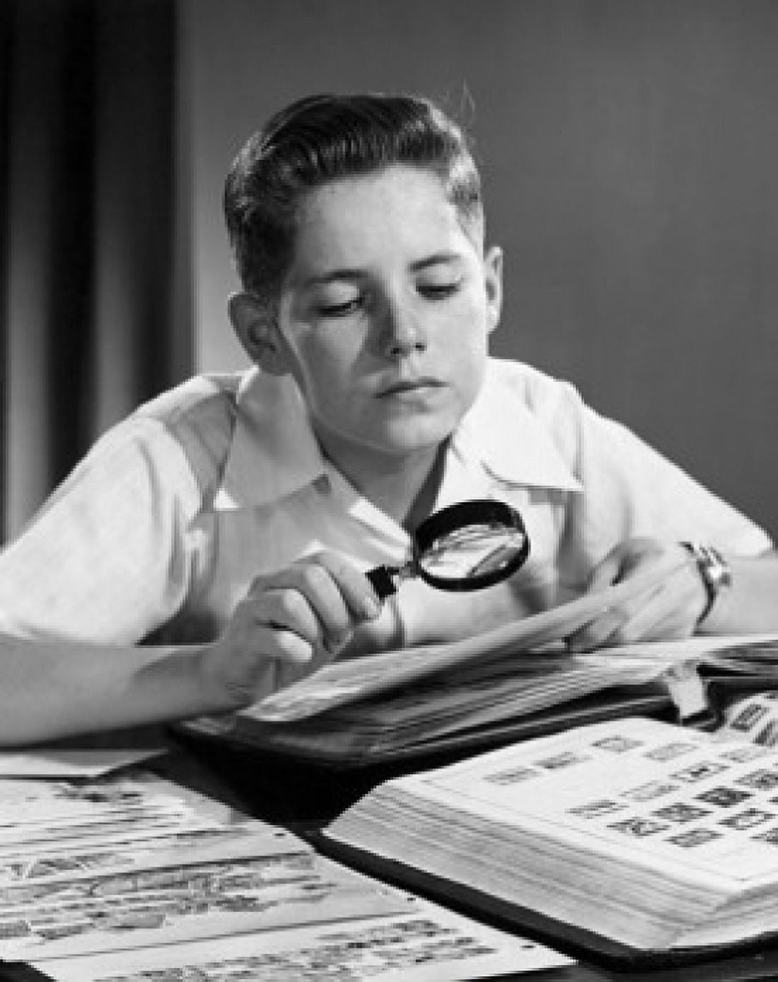Boy looking at postage stamps through a magnifying glass Canvas Art - (18 x 24)