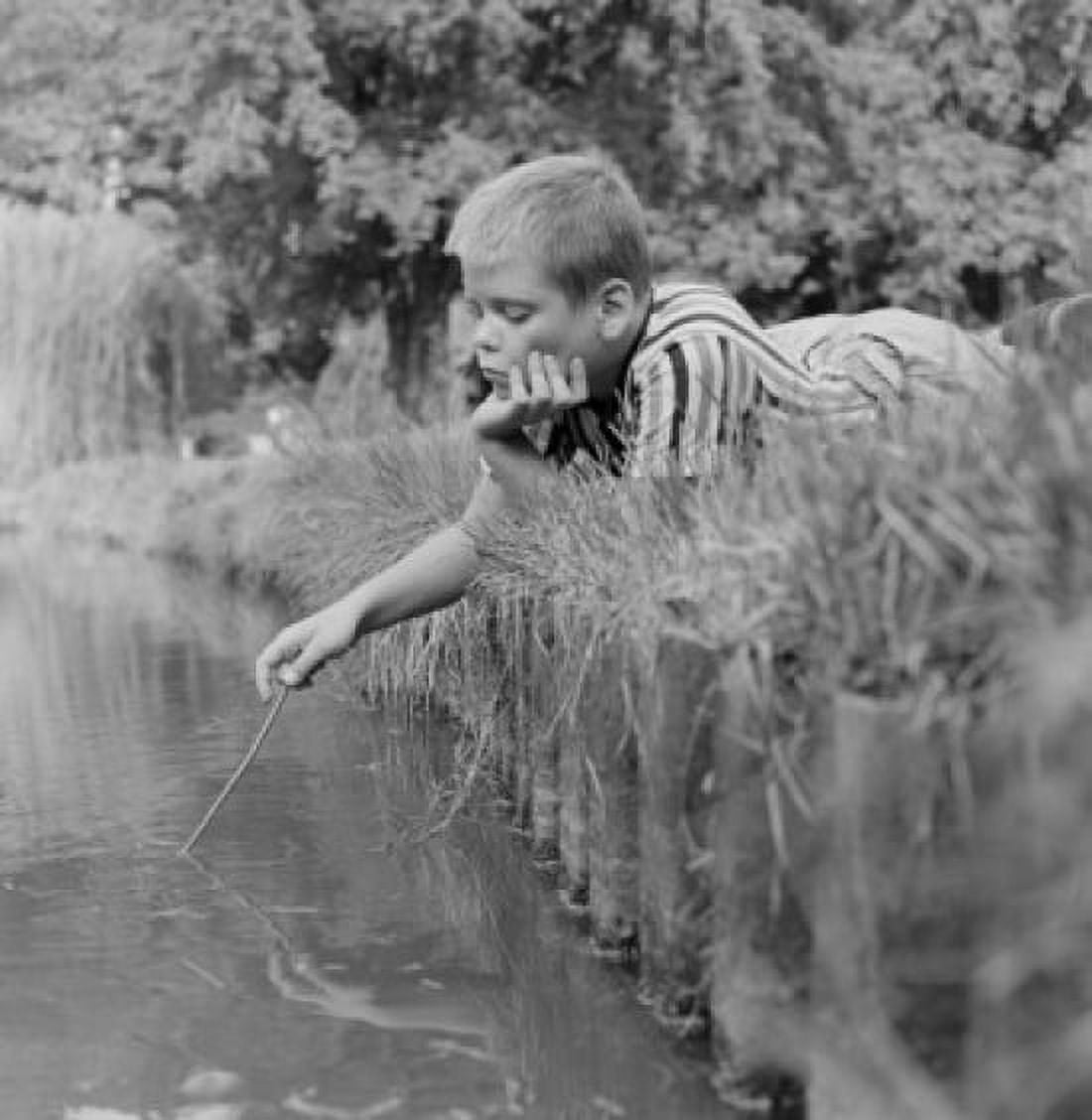 Boy lying in grass on bank of stream Canvas Art - (18 x 24)
