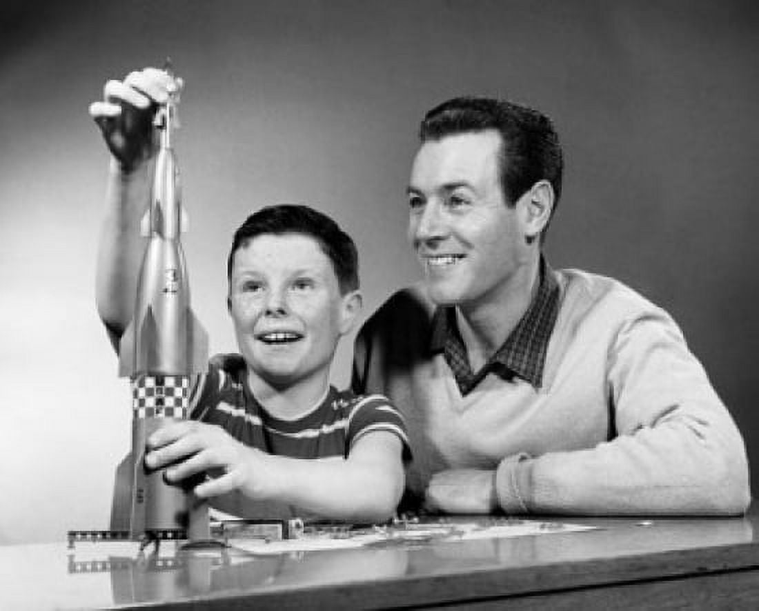 Boy playing with a model rocket with his father beside him Canvas Art - (24 x 36)