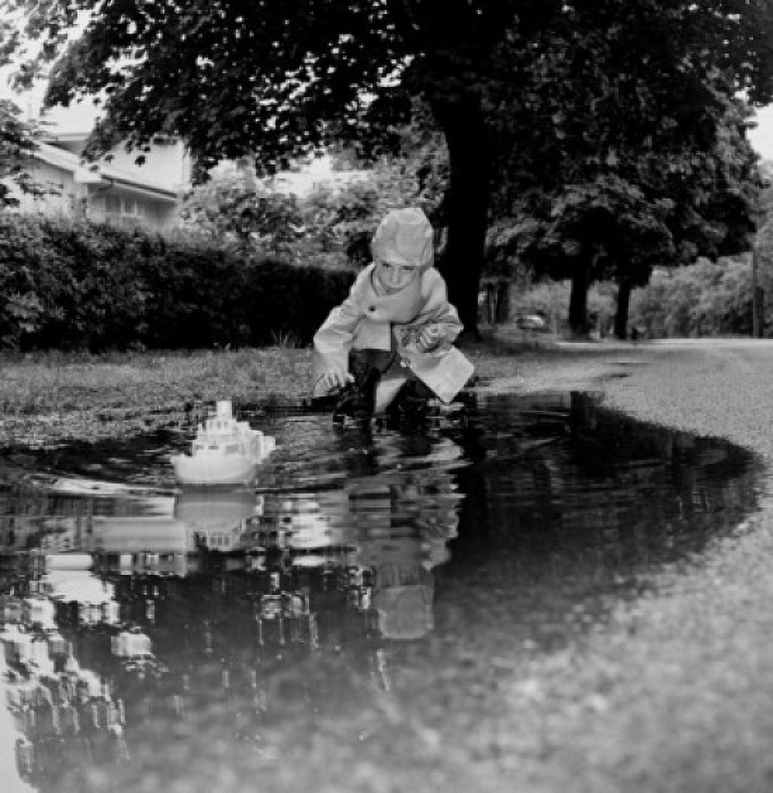 Boy playing with toy boat in puddle Canvas Art - (24 x 36)