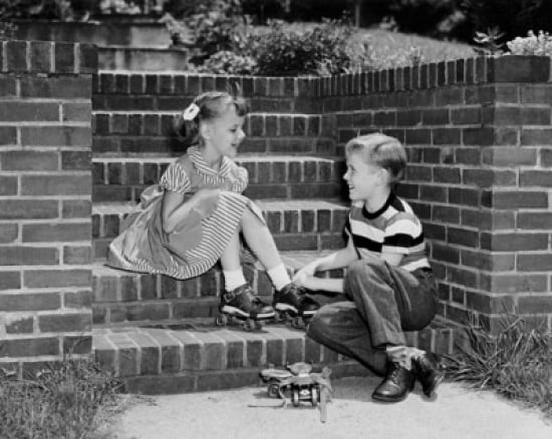 Boy putting a roller skate on his sisters foot Canvas Art - (18 x 24)