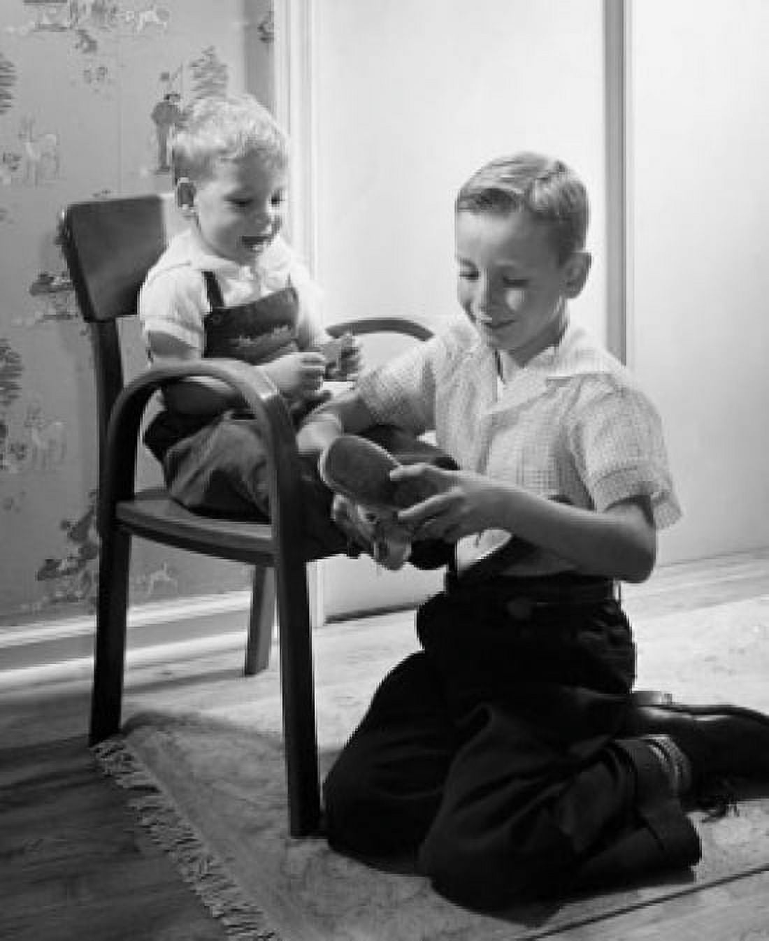 Boy putting shoes on his brothers feet Canvas Art - (24 x 36)