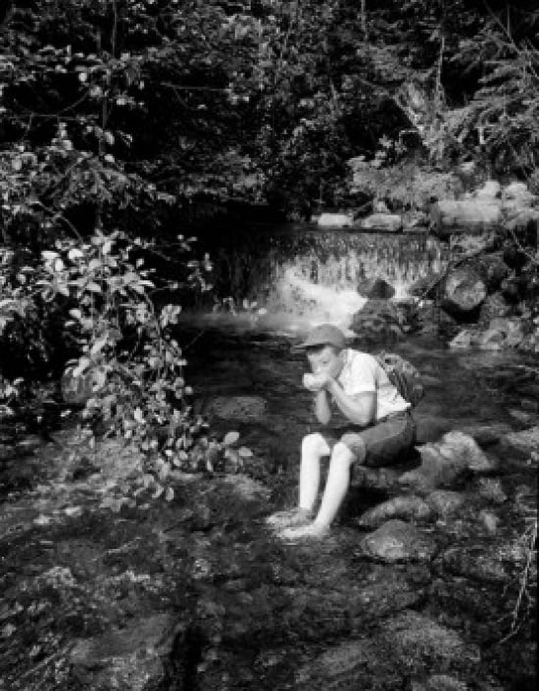 Boy sitting and drinking water from mountain stream Canvas Art - (18 x 24)