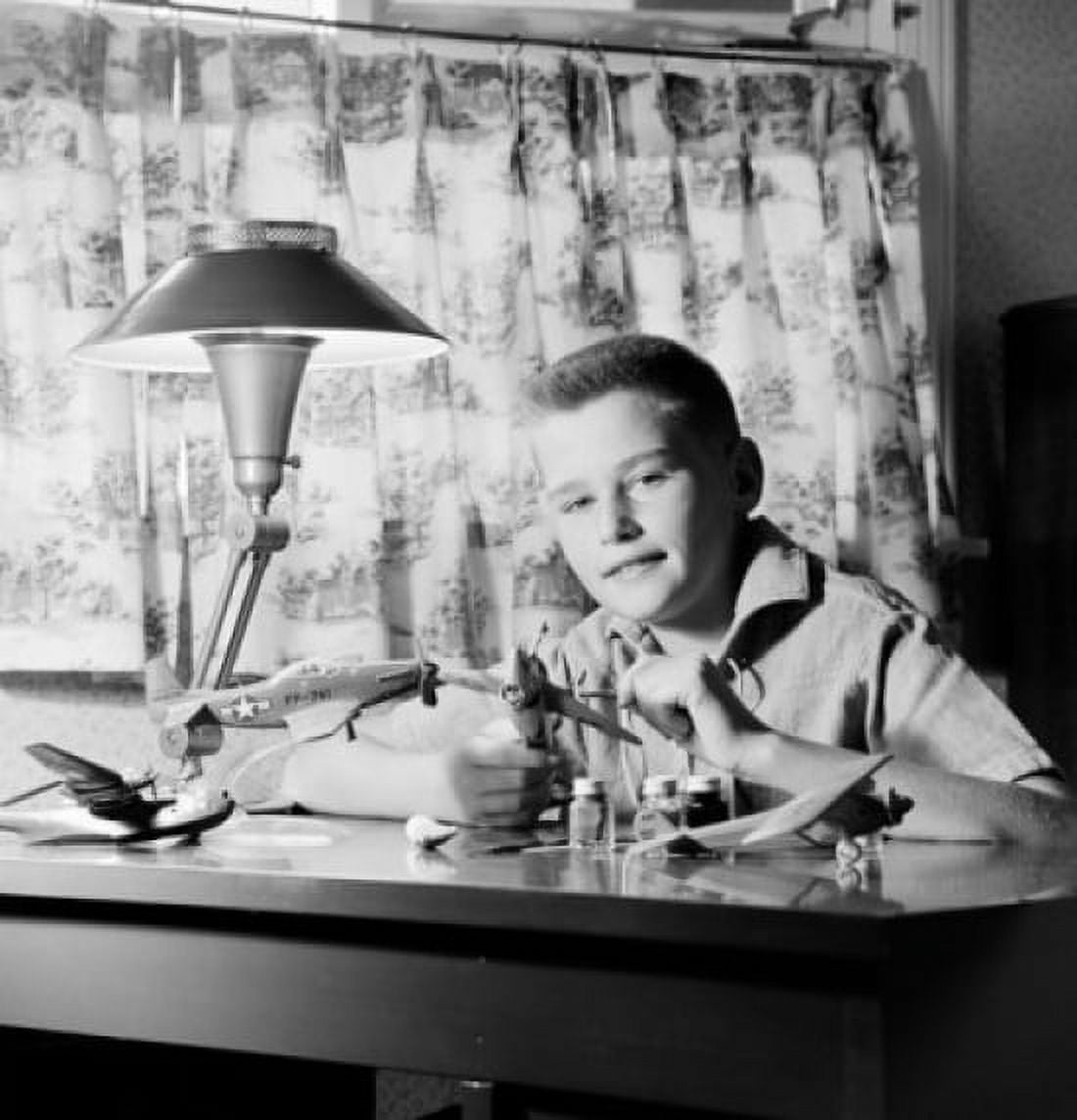 Boy sitting at desk and making model plane Canvas Art - (24 x 36)