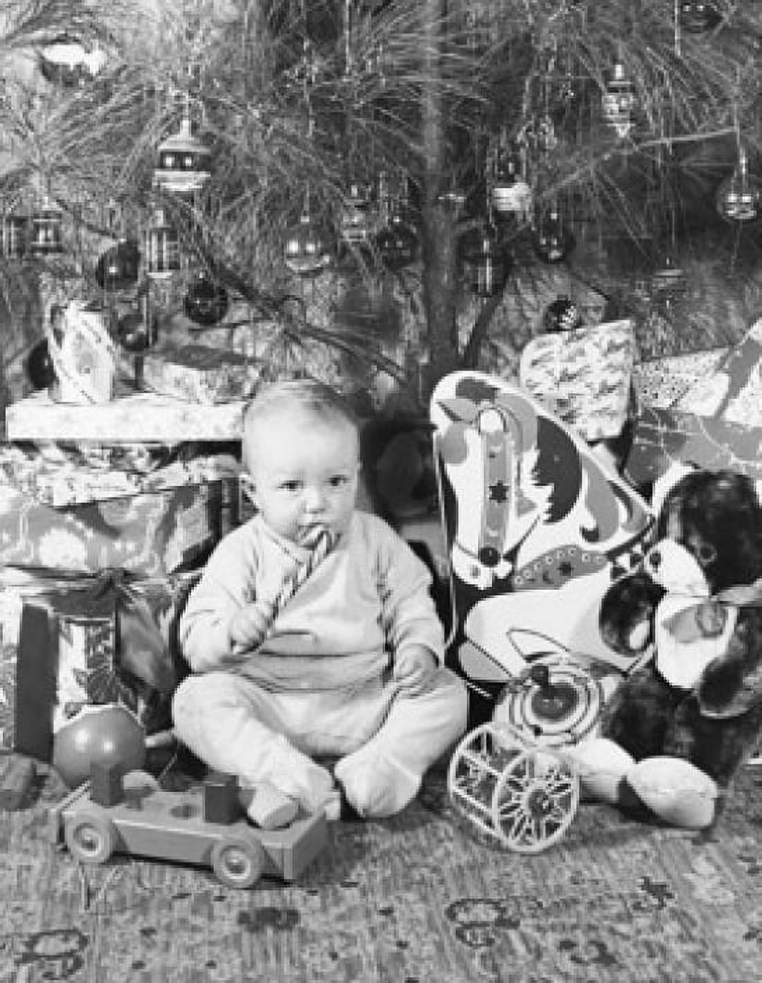 Boy sitting near Christmas presents and eating a candy cane Canvas Art - (24 x 36)