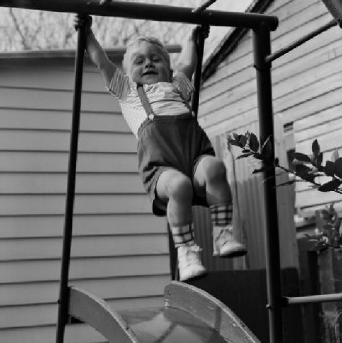 Boy swinging on slide outside house Canvas Art - (24 x 36)