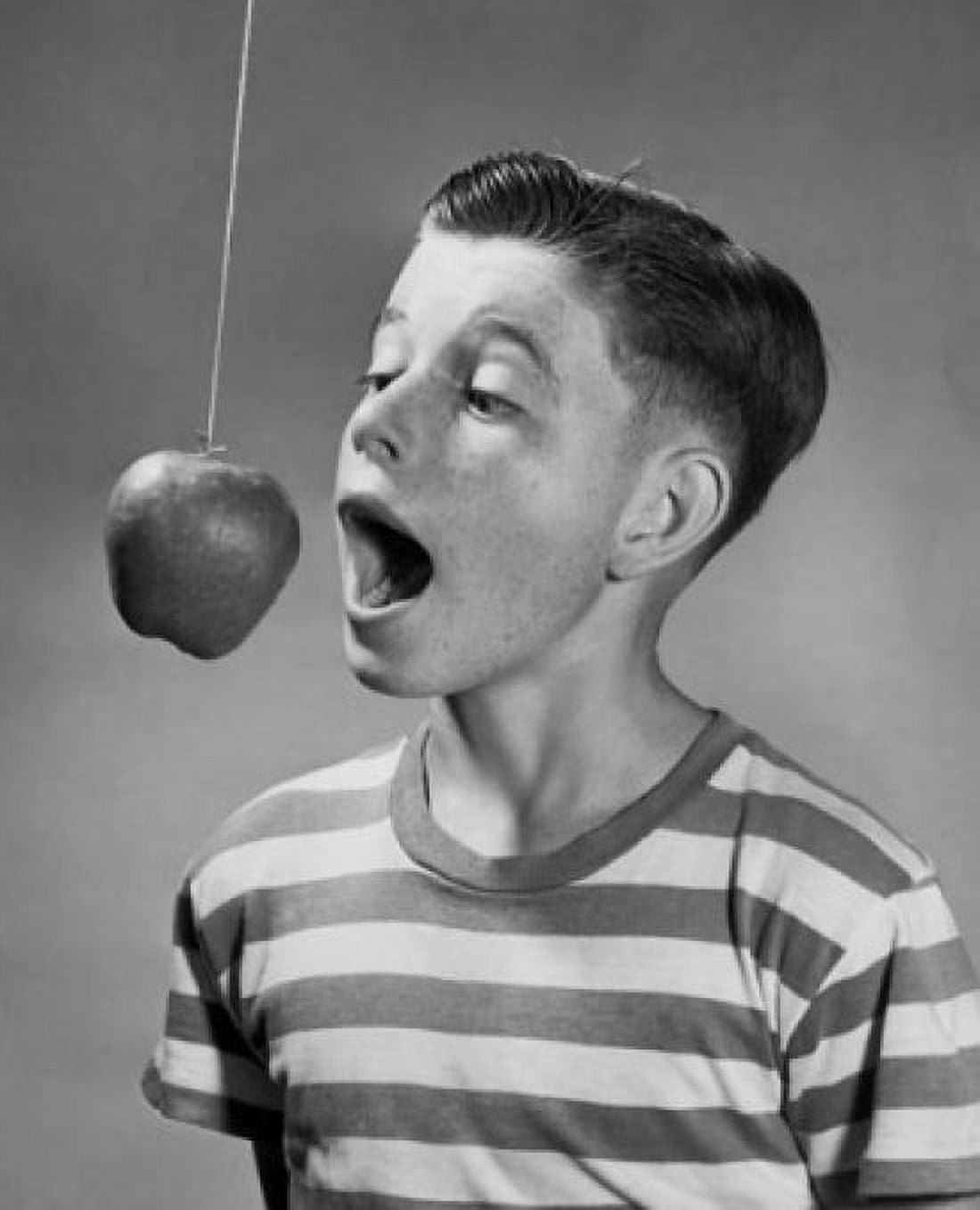 Boy trying to bite an apple hanging on a string Canvas Art - (18 x 24)