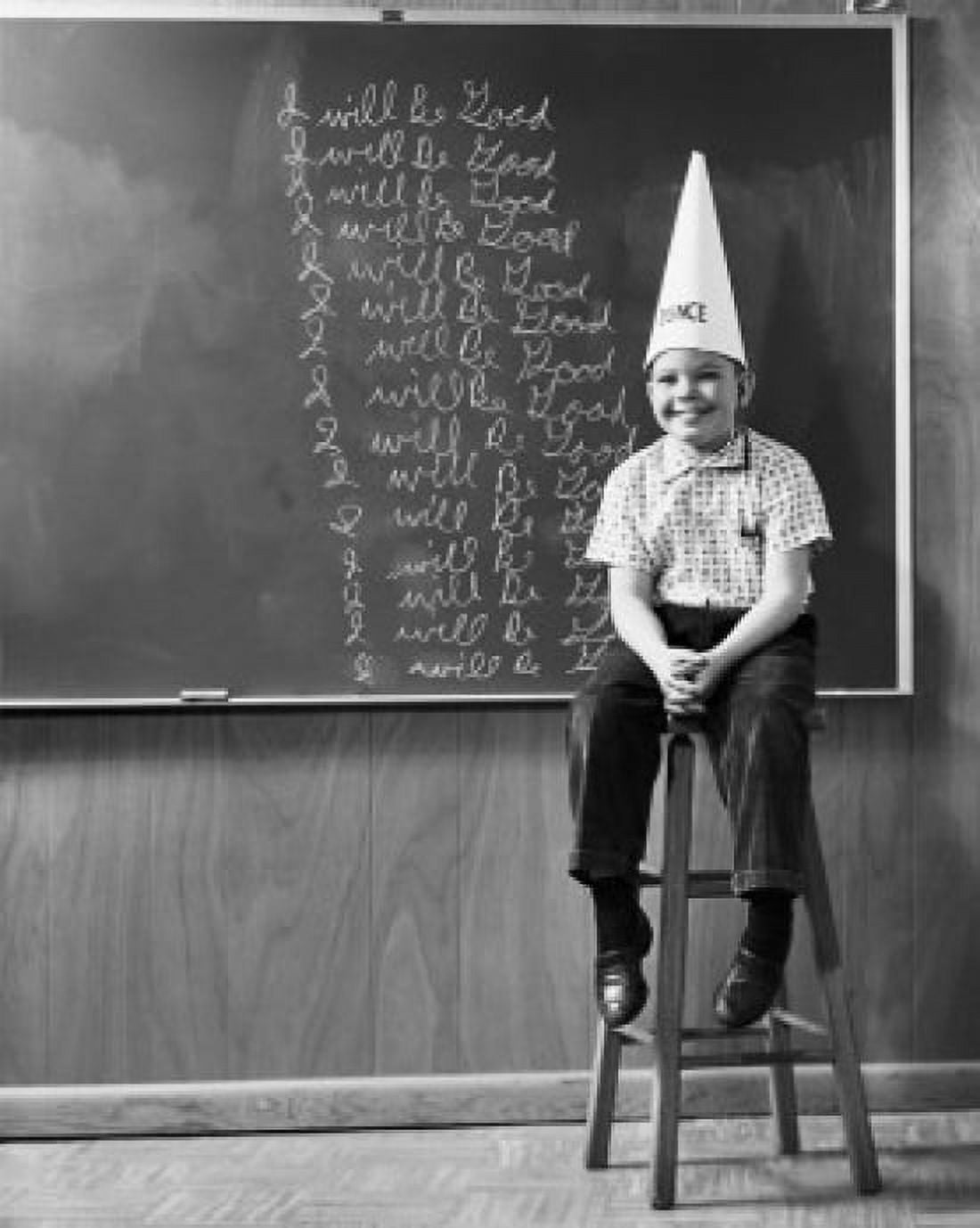 Boy wearing a dunce cap sitting in front of a blackboard Canvas Art - (24 x 36)