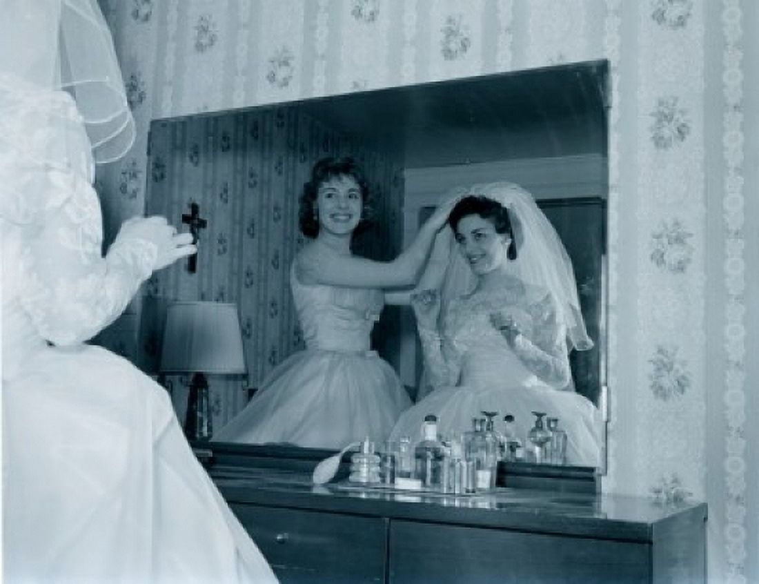 Bridesmaid attaching veil to brides hair in front of mirror Canvas Art - (24 x 36)