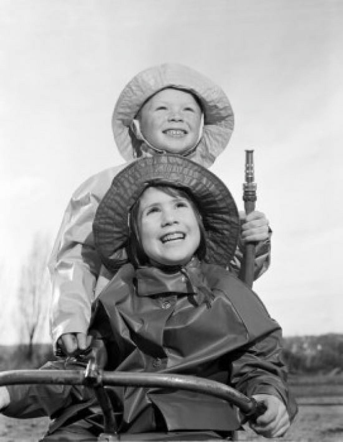 Brother and sister wearing rain coats and holding garden hose Canvas Art - (18 x 24)