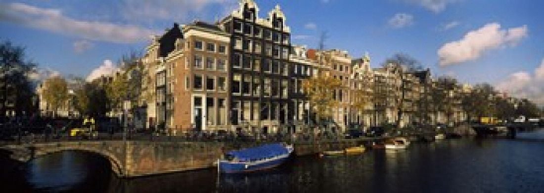 Buildings along a canal Amsterdam Netherlands Canvas Art - Panoramic Images (18 x 7)