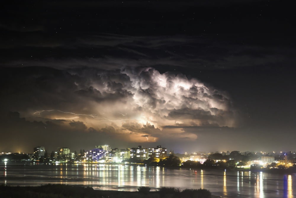 Buildings along the coastline illuminated and reflected in the water at nighttime Brisbane Queensland Australia Canvas Art - John Short Design Pics (19 x 12)
