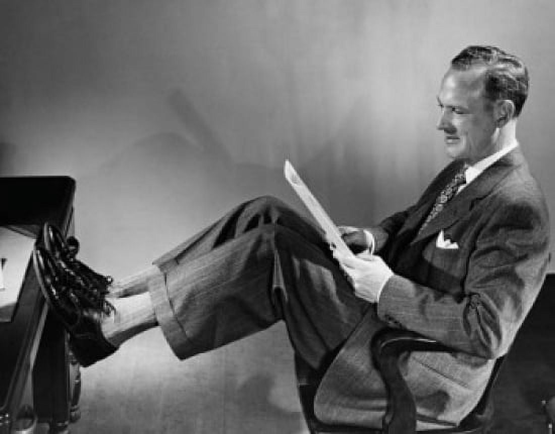 Businessman reading a paper with his legs resting on a desk Canvas Art - (24 x 36)