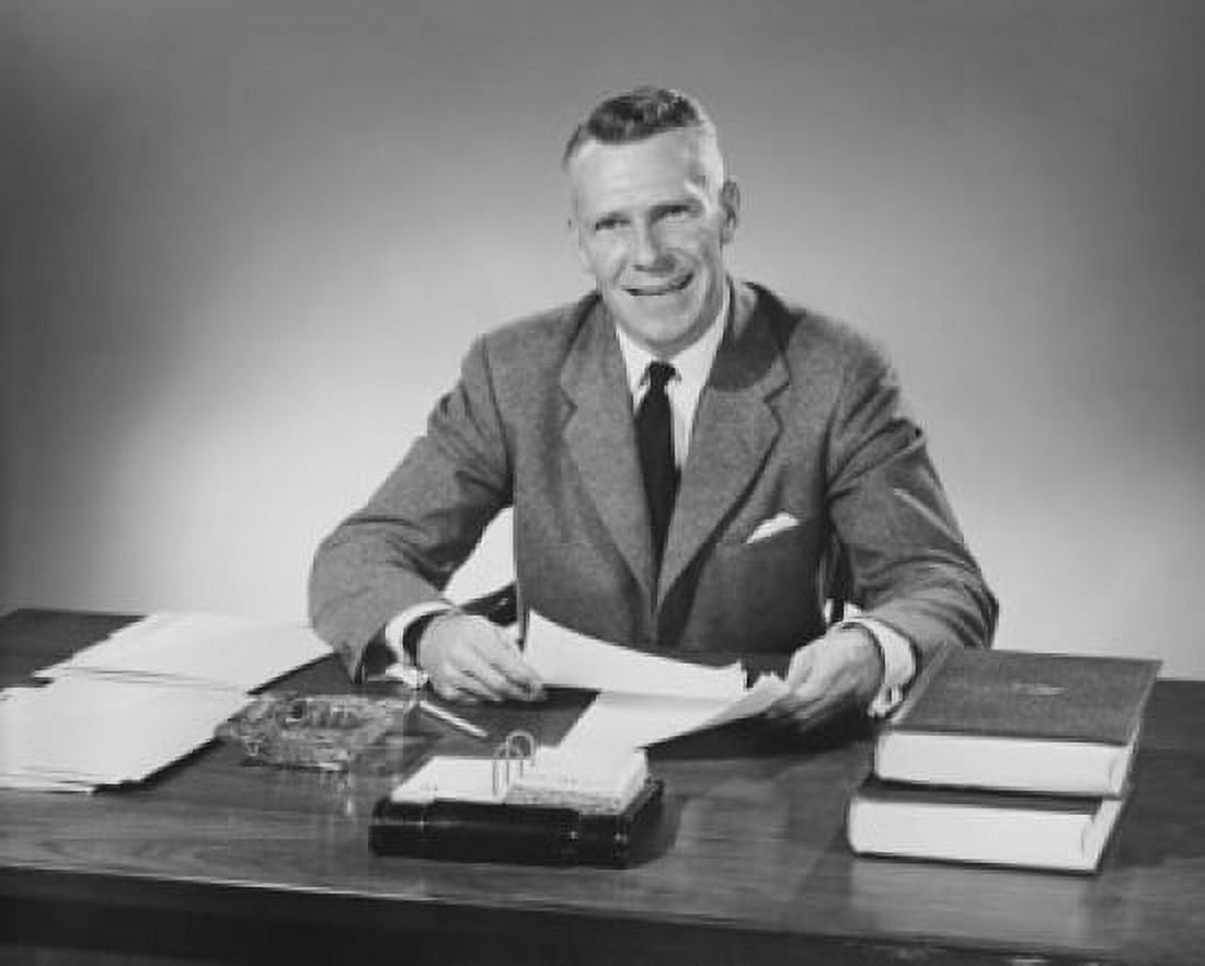 Businessman sitting at a desk and holding documents in an office Canvas Art - (18 x 24)