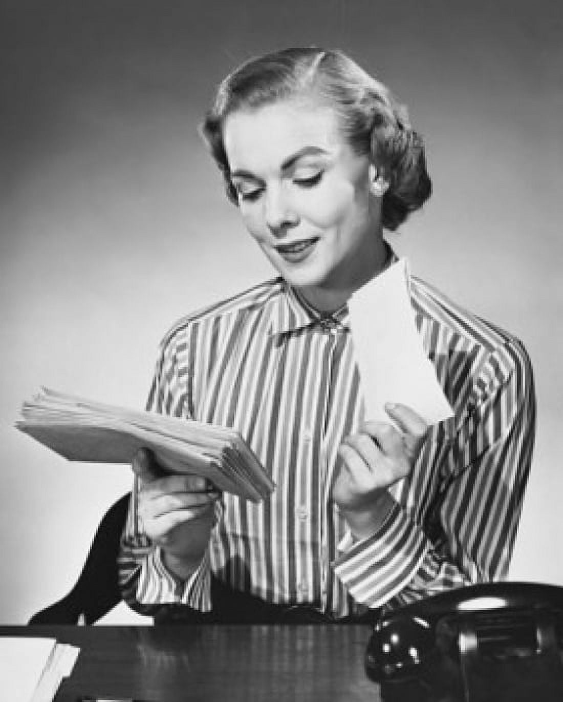 Businesswoman sitting at a desk and holding letters in an office Canvas Art - (24 x 36)