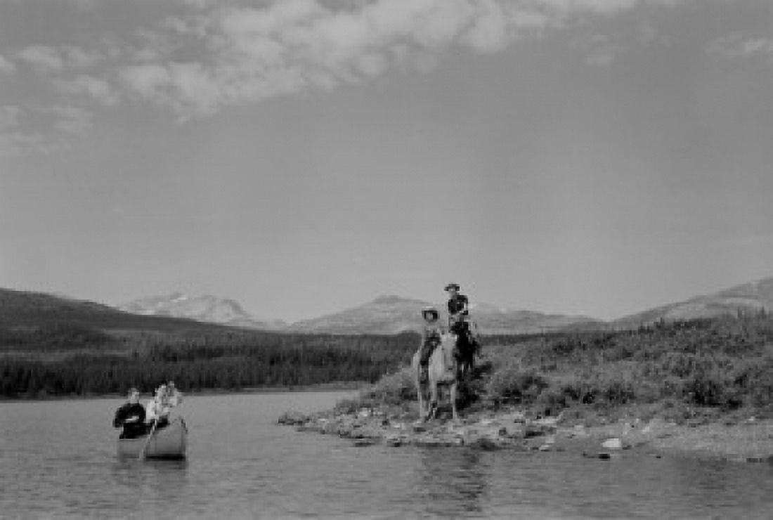 Canada Canadian Rockies Maligne Lake Couple canoeing while two riders are watching from shore Canvas Art - (18 x 24)