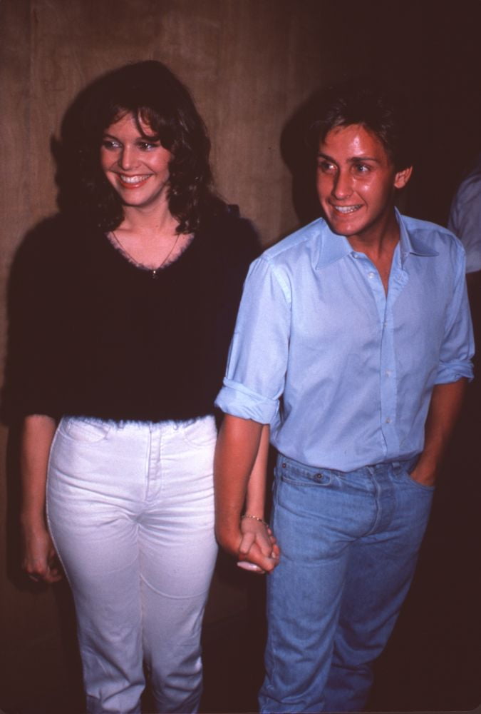 Carey Salley In Fuzzy Black Top And White Pants Holding Hands With