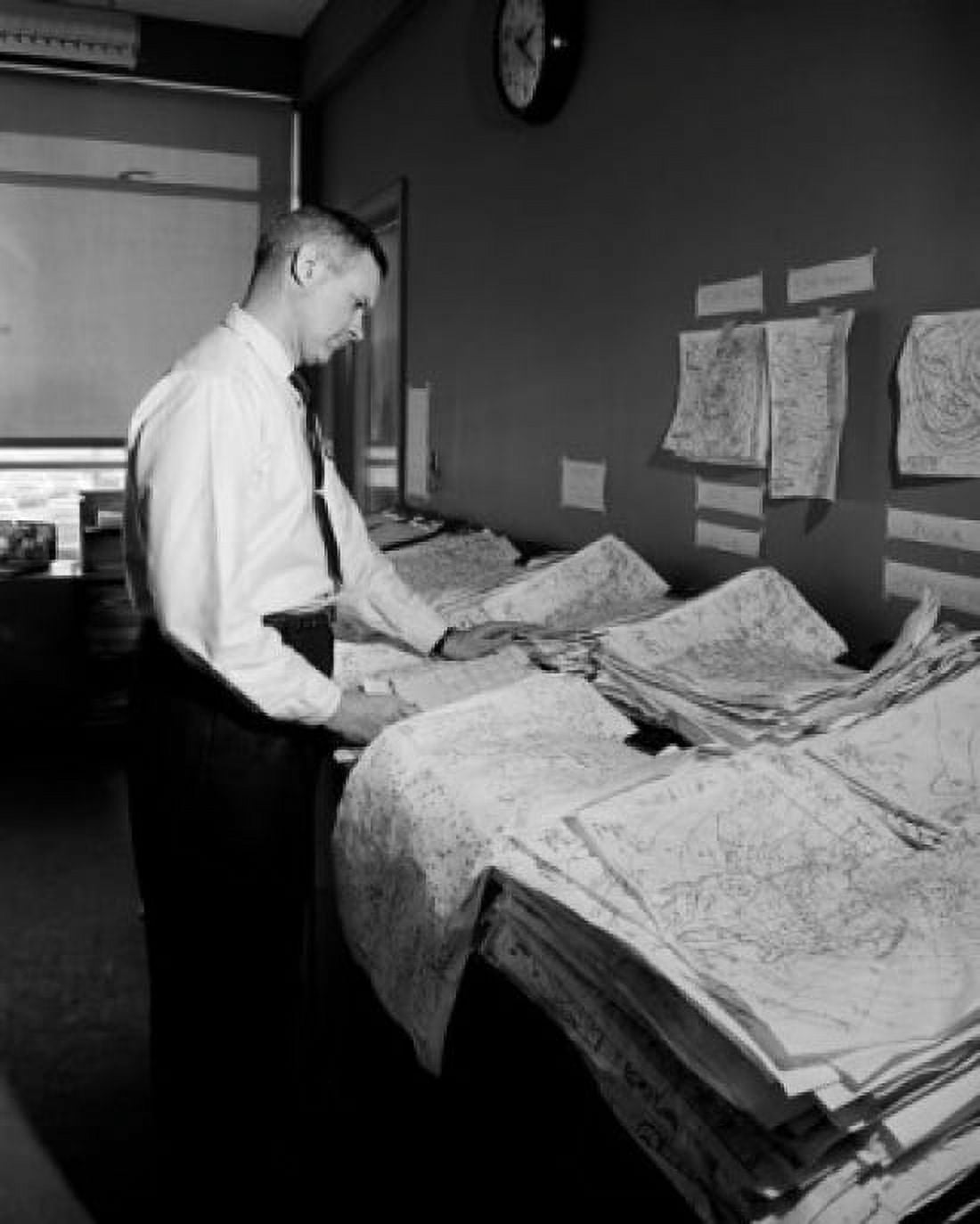 Cartographer standing next to piles of maps Canvas Art - (24 x 36)