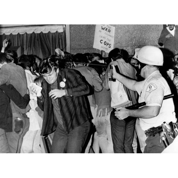 Chicago Police Officer (Right) Uses Pressure Can To Squirts Mace At Anti-Vietnam War Demonstrators. The Protest Was Outside The Conrad Hilton Hotel During The 1968 Democratic National Convention. Aug.