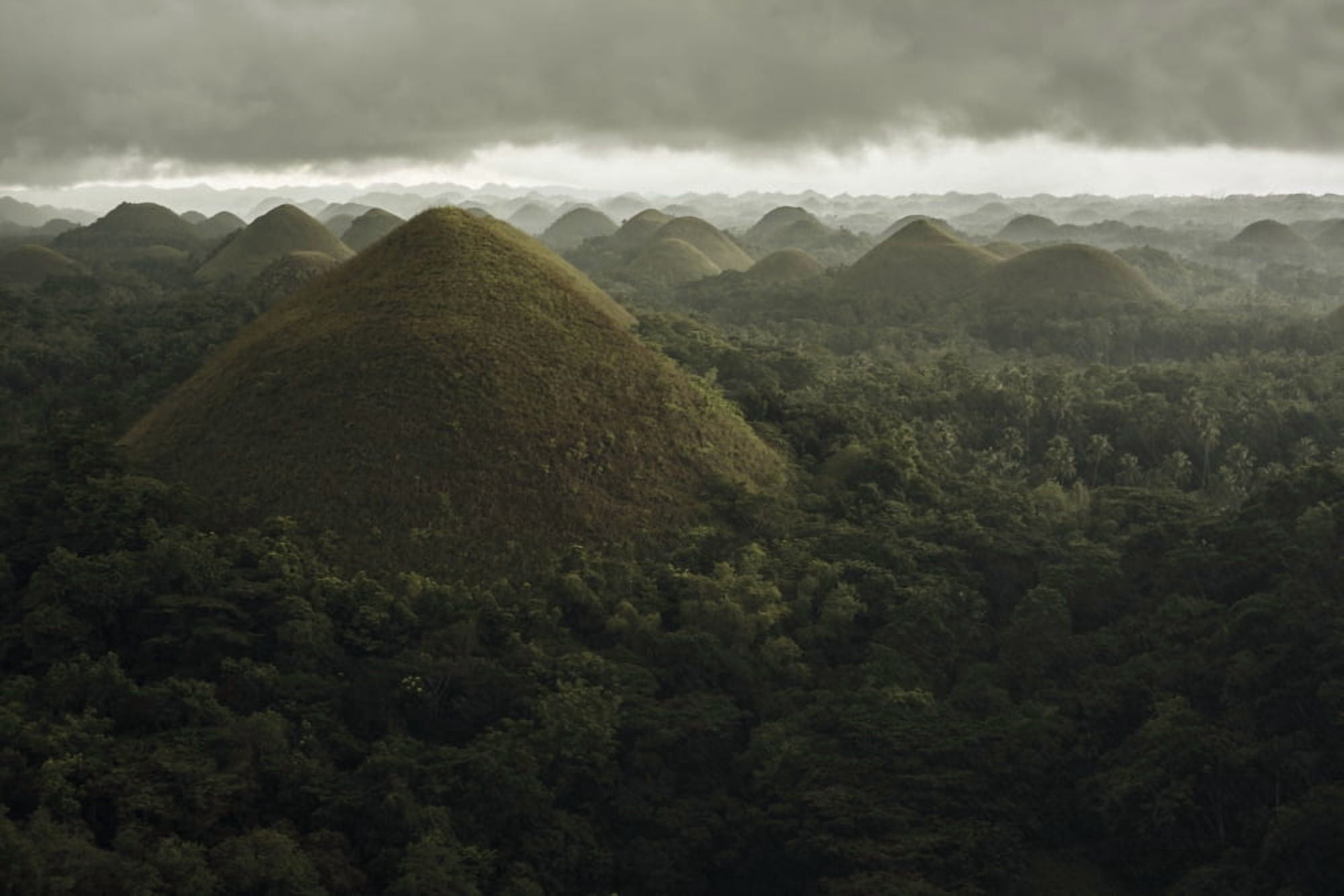 Chocolate hills landscape from Bohol Island a big storm covers the sky making an interesting lighting effect Carmen Bohol Island Philippines Canvas Art - Luis Martinez Design Pics (18 x 12)