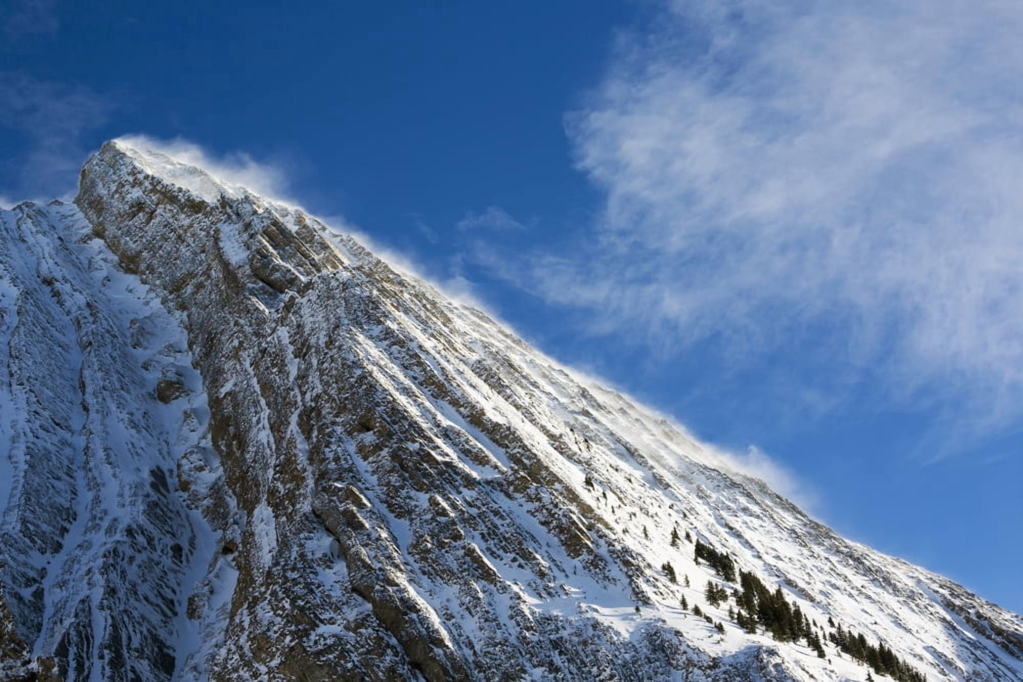Close up of a snow covered mountain peak with wind blowing snow off the slope with blue sky and clouds Kananaskis Country Alberta Canada Canvas Art - Michael Interisano Design Pics (19 x 12)