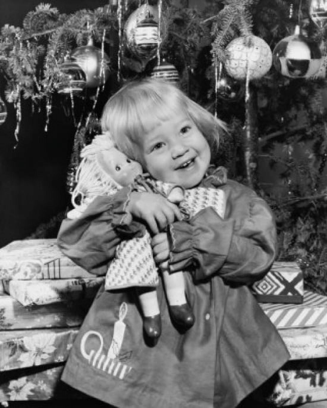 Close-up of a girl standing in front of Christmas presents and hugging a doll Canvas Art - (18 x 24)