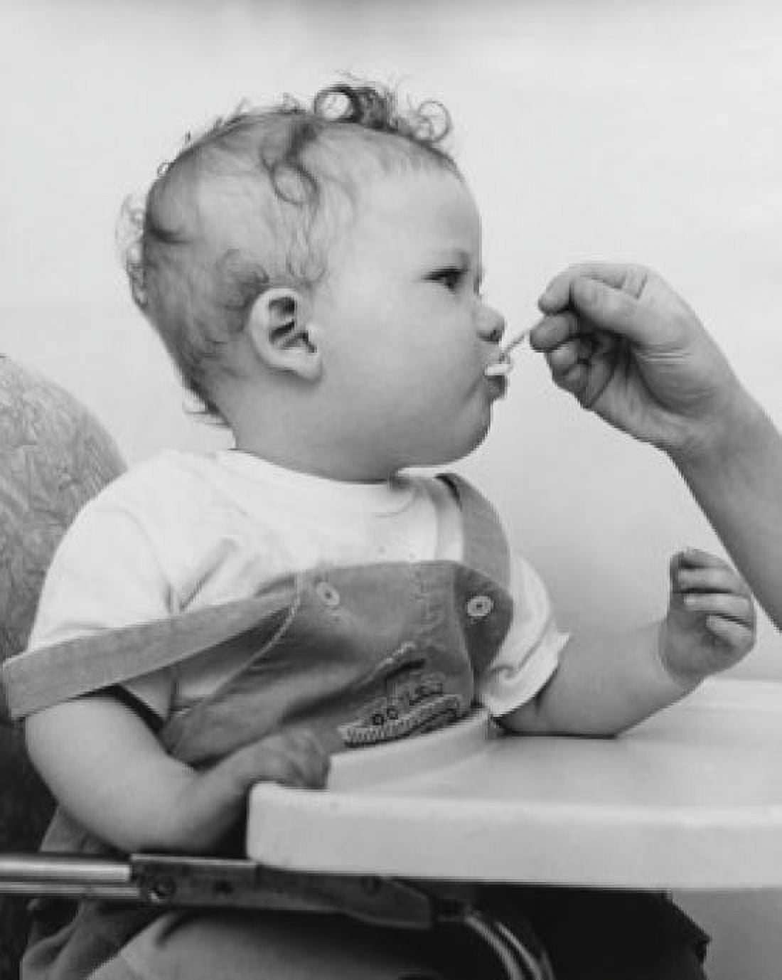Close-up of a persons hand feeding a baby sitting in a high chair Canvas Art - (18 x 24)