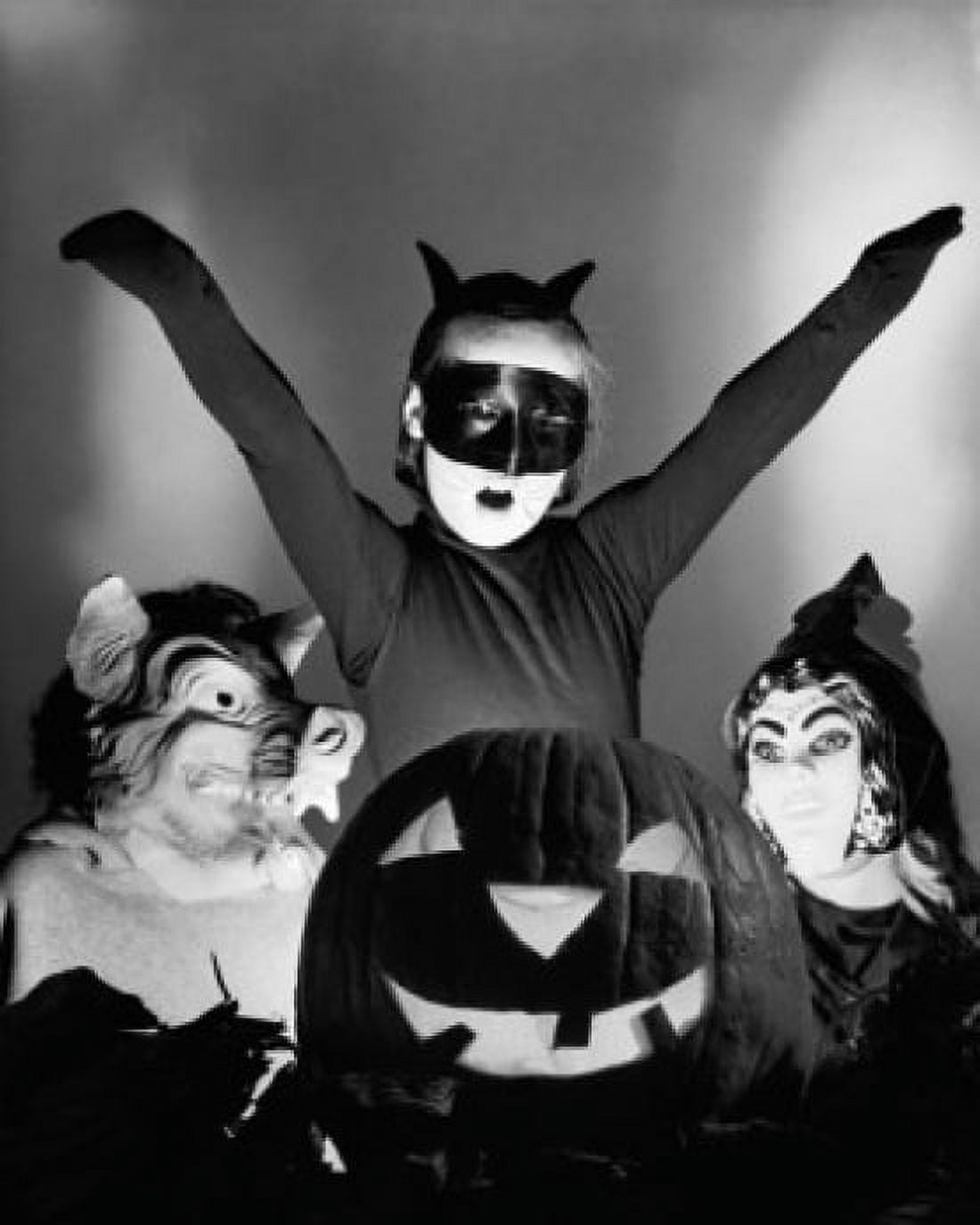 Close-up of an illuminated jack o lantern with three people wearing Halloween costumes behind it Canvas Art - (18 x 24)