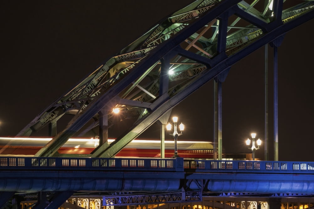 Close up of the illuminated arch of a bridge and lamp posts at nighttime Canvas Art - John Short Design Pics (19 x 12)