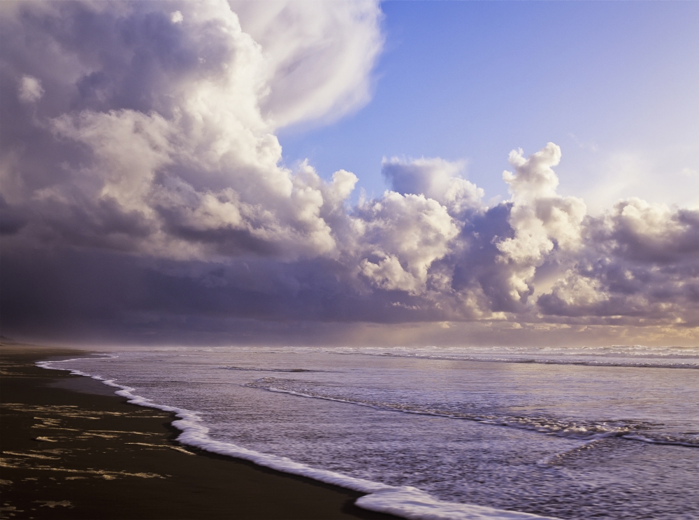 Clouds and tide moving onto the shore along the beach; Winchester Bay